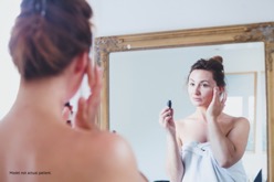 Woman applying skin care products in the mirror