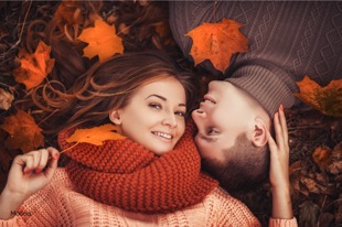 man and woman laying in a pile of leaves
