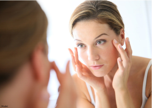 Woman putting cream on around her eyes