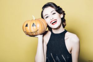 Woman in a black dress smiling with a jack-o'-lantern