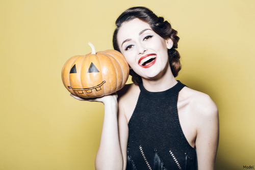 Woman in a black dress smiling with a jack-o'-lantern