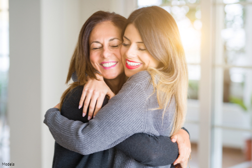 Adult daughter and mother hugging and smiling