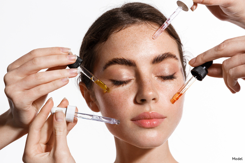 Woman applying several skin care serums to her face