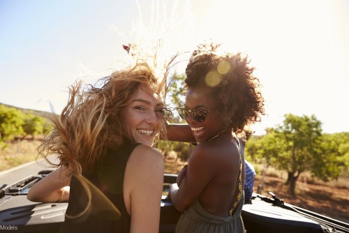 Two friends smiling outdoors in the sun