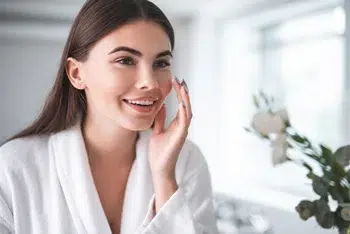 a happy woman touches her fair, smooth face after receiving acne treatment solution at Belle Marin Aesthetics