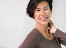 Confident woman smiling with her hand gently touching her neck