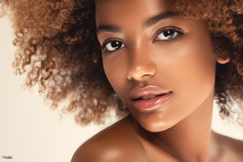 Woman with glowing skin and full lips softly smiling