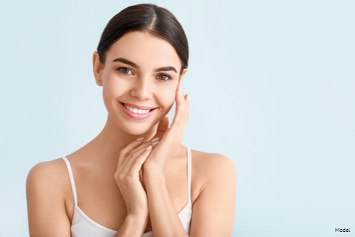 Woman with clear skin gently touching her face and smiling