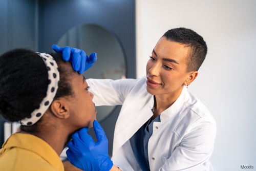 Female doctor examining a female patient's face