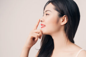 A profile shot of a woman touching her nose after liquid rhinoplasty