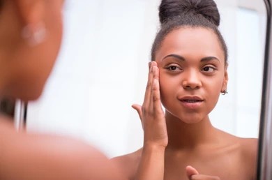 A woman looking in the mirror after a Secret RF microneedling treatment in Marin County