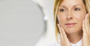 Woman looking in the mirror after microneedling in Mill Valley, CA