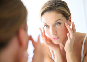 Woman looking in the mirror at broken capillaries before BBL HERO treatment